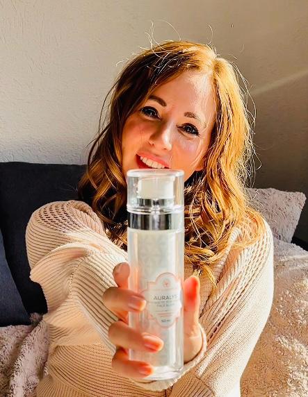 Frau streckt den AURALYS Flakon in die Kamera